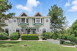 A two-story house with a green facade, a covered porch, and a well-maintained garden. - Magical Townhome Near Disney w Resort Pool Access (Orlando)