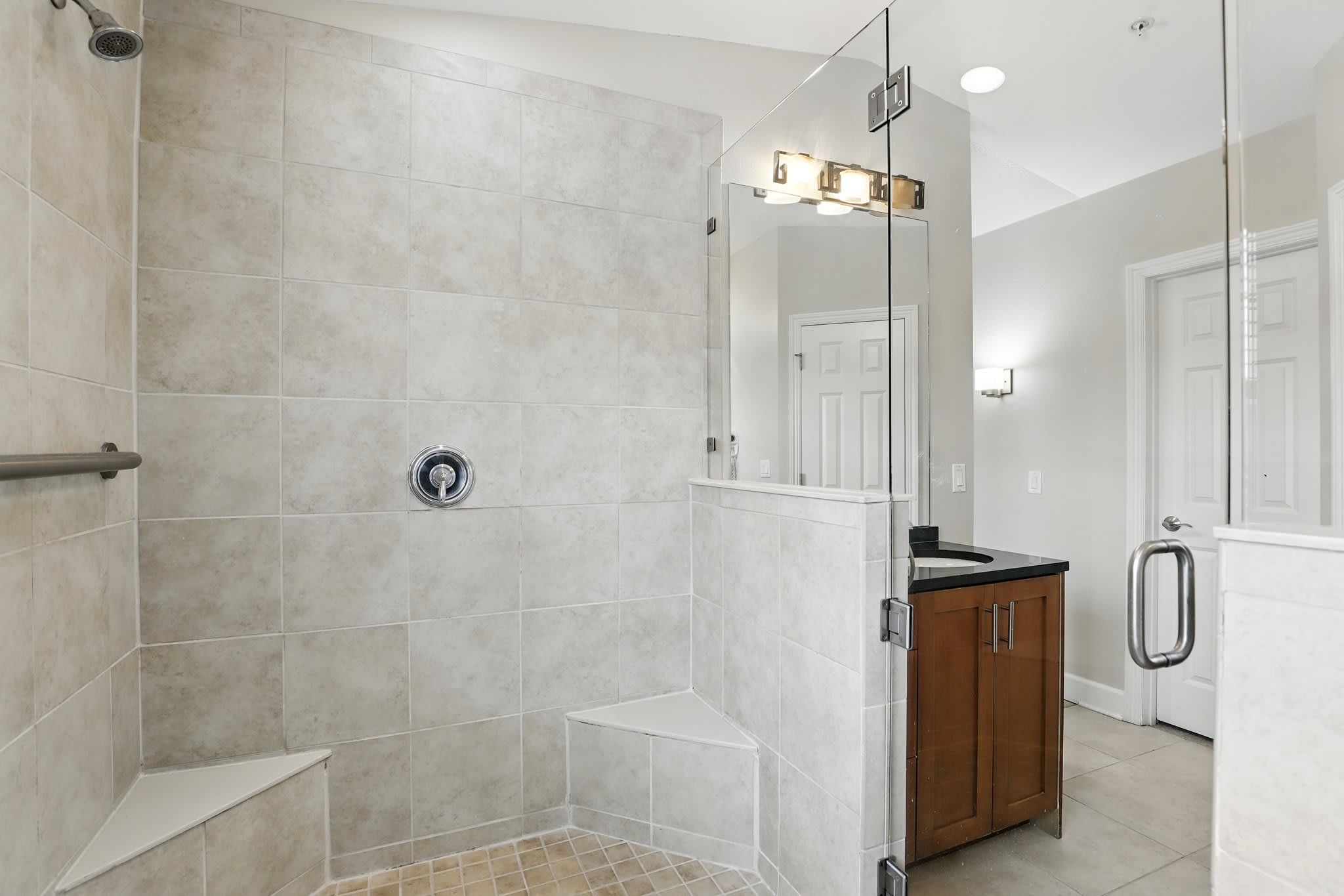 A modern bathroom with a walk-in shower, a vanity with a mirror, and a toilet.