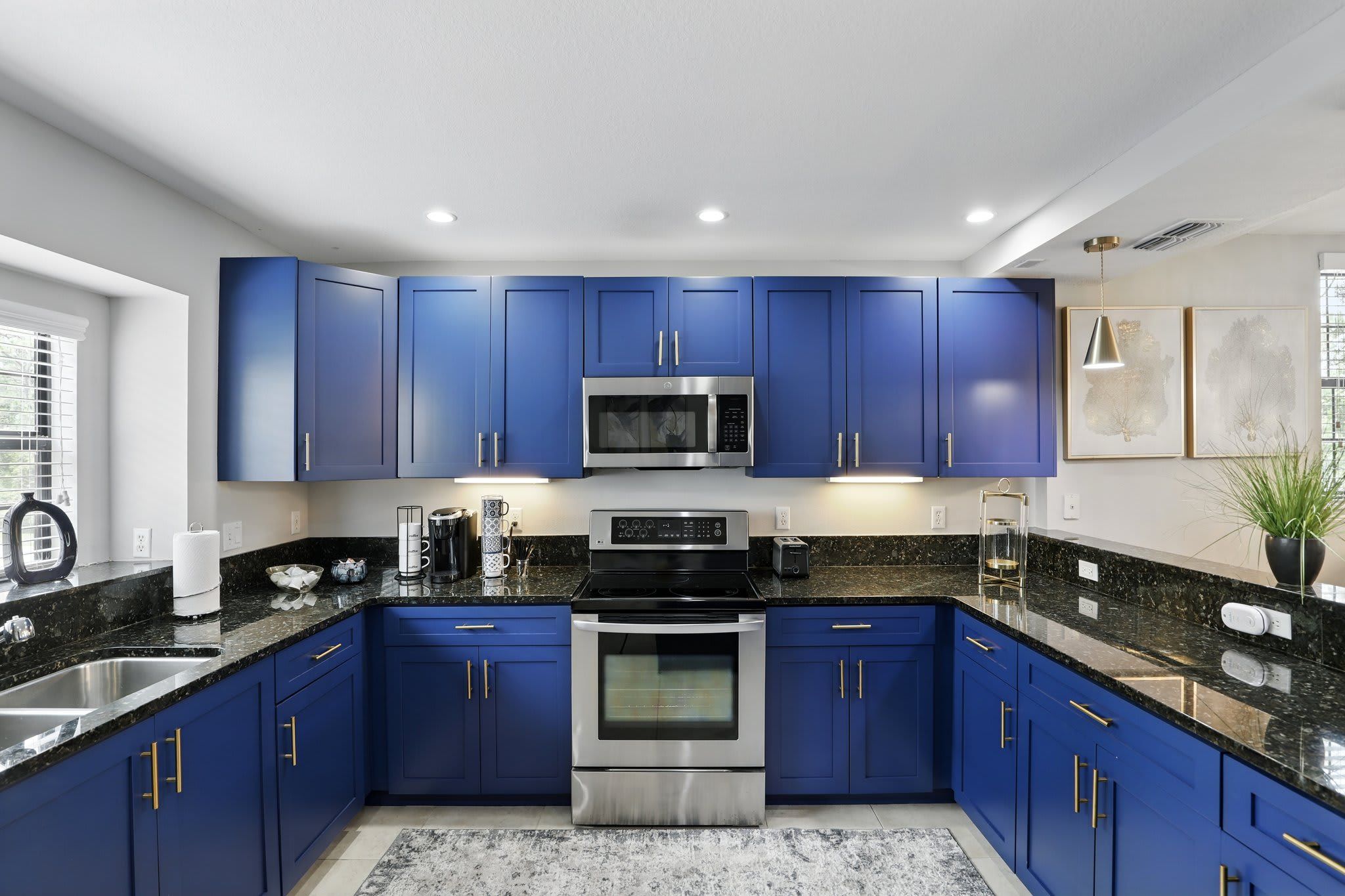 Una cocina moderna con armarios azules, electrodomésticos de acero inoxidable y una encimera de granito.