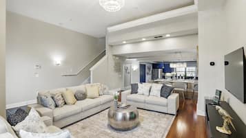 A spacious living room with a large sofa set, a coffee table, and a chandelier.