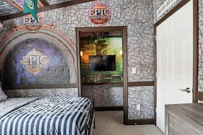 Una habitación con cama, televisión y una pared de piedra con señalización de 'Universal Epic Universe'.