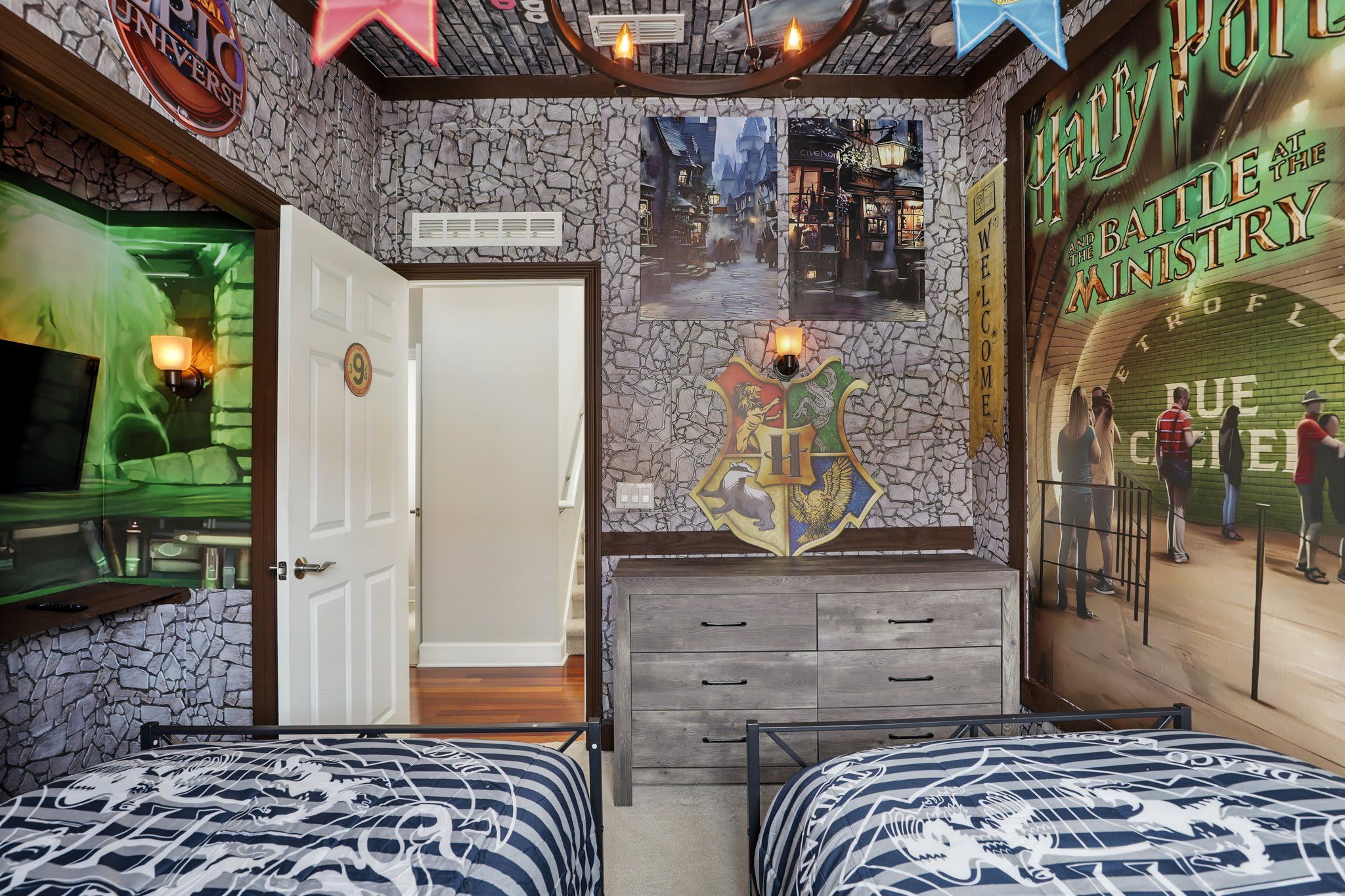 Una habitación con paredes de piedra, un cartel grande de un mundo mágico, un aparador de madera y dos camas con ropa de cama estampada.