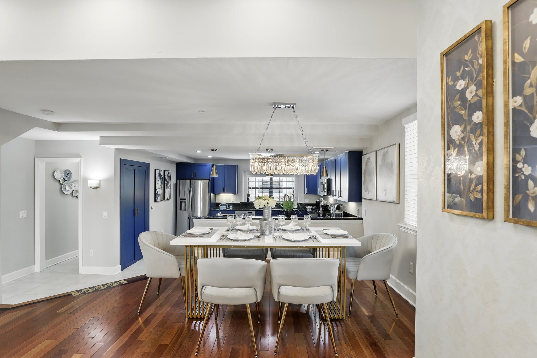 A modern dining area with a white table set for four, surrounded by white chairs.