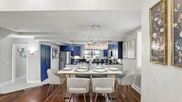 A modern dining area with a white table set for four, surrounded by white chairs.