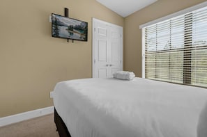 A bedroom with a bed, a door, a window with blinds, and a painting on the wall. - 4 BD Townhome Close to Disney! (Orlando)