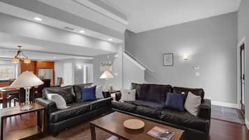 Una sala de estar moderna con un sofá modular, una mesa de centro y un comedor con muebles de madera.