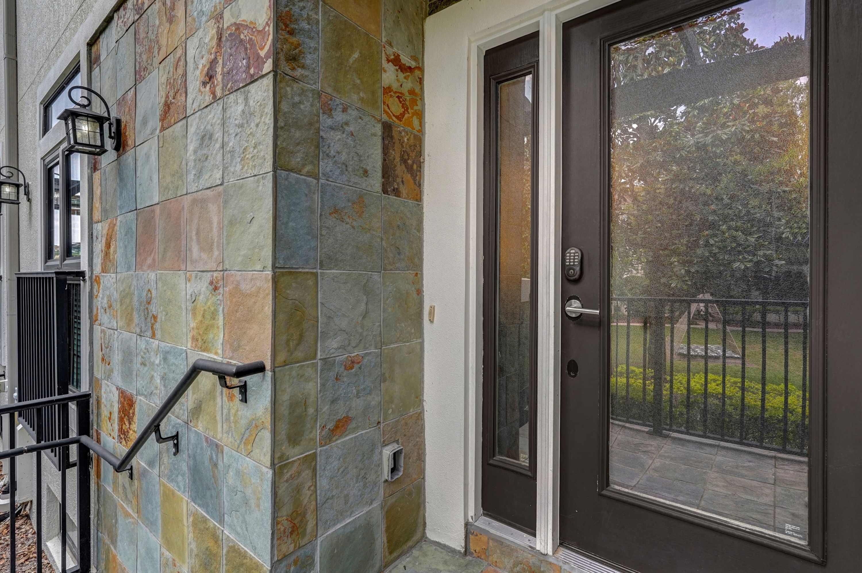 A residential building with a stone facade, a black metal gate, and a glass door with a metal handle.