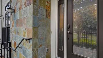 A residential building with a stone facade, a black metal gate, and a glass door with a metal handle.