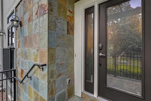 A residential building with a stone facade, a black metal gate, and a glass door with a metal handle. - 4 BD Townhome Close to Disney! (Orlando)