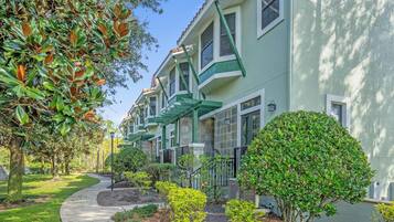 A row of townhouses with green awnings, a curved pathway, and well-maintained landscaping.