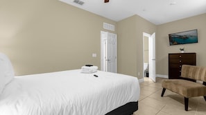 A bedroom with a bed, a chair, a dresser, and a television on the wall. - Family Disney Getaway With Pool, Spa and Billiards (Orlando)