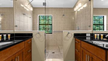 A modern bathroom with dual sinks, a shower area, and a window providing natural light.