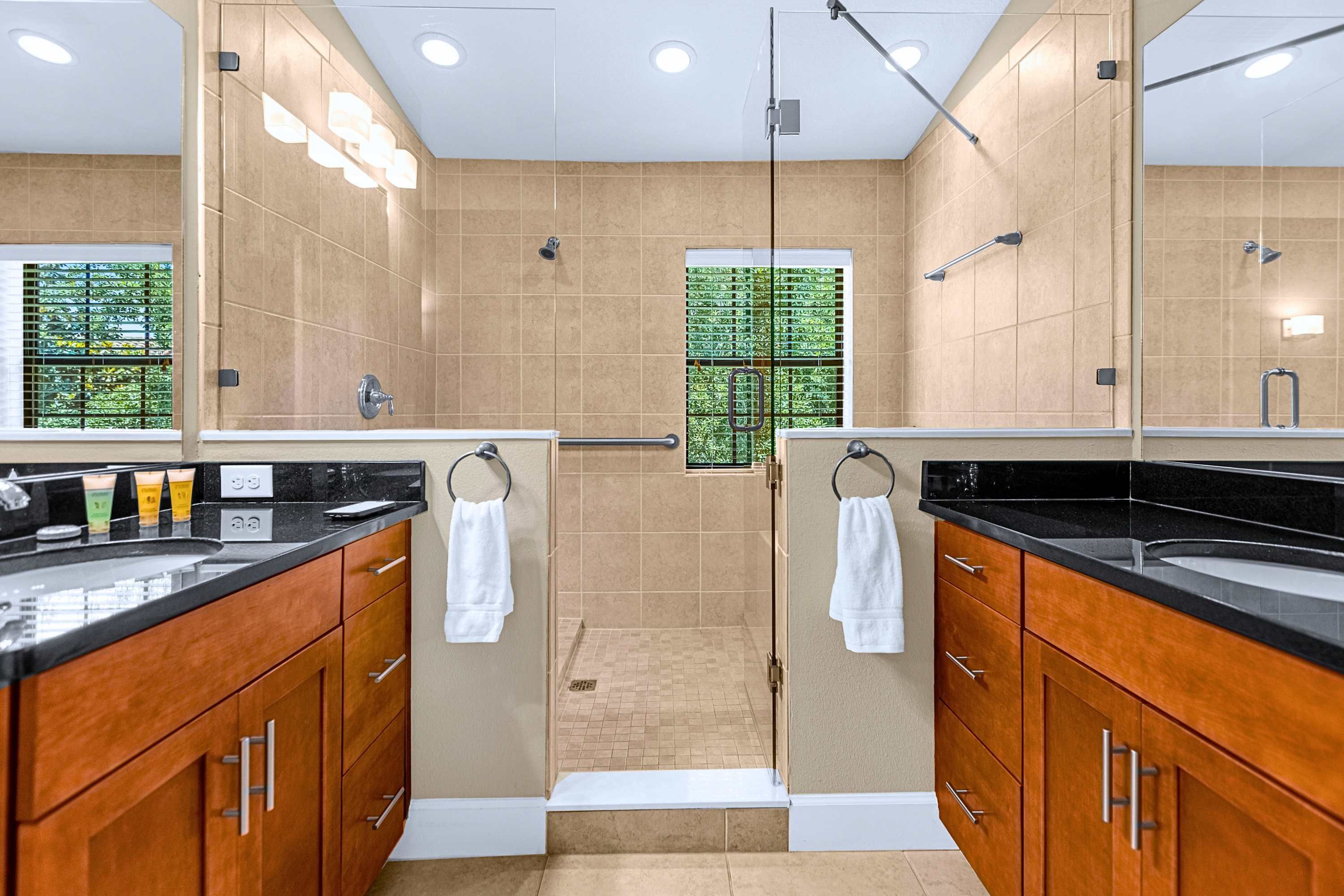 A modern bathroom with a walk-in shower, wooden cabinets, and a large mirror.