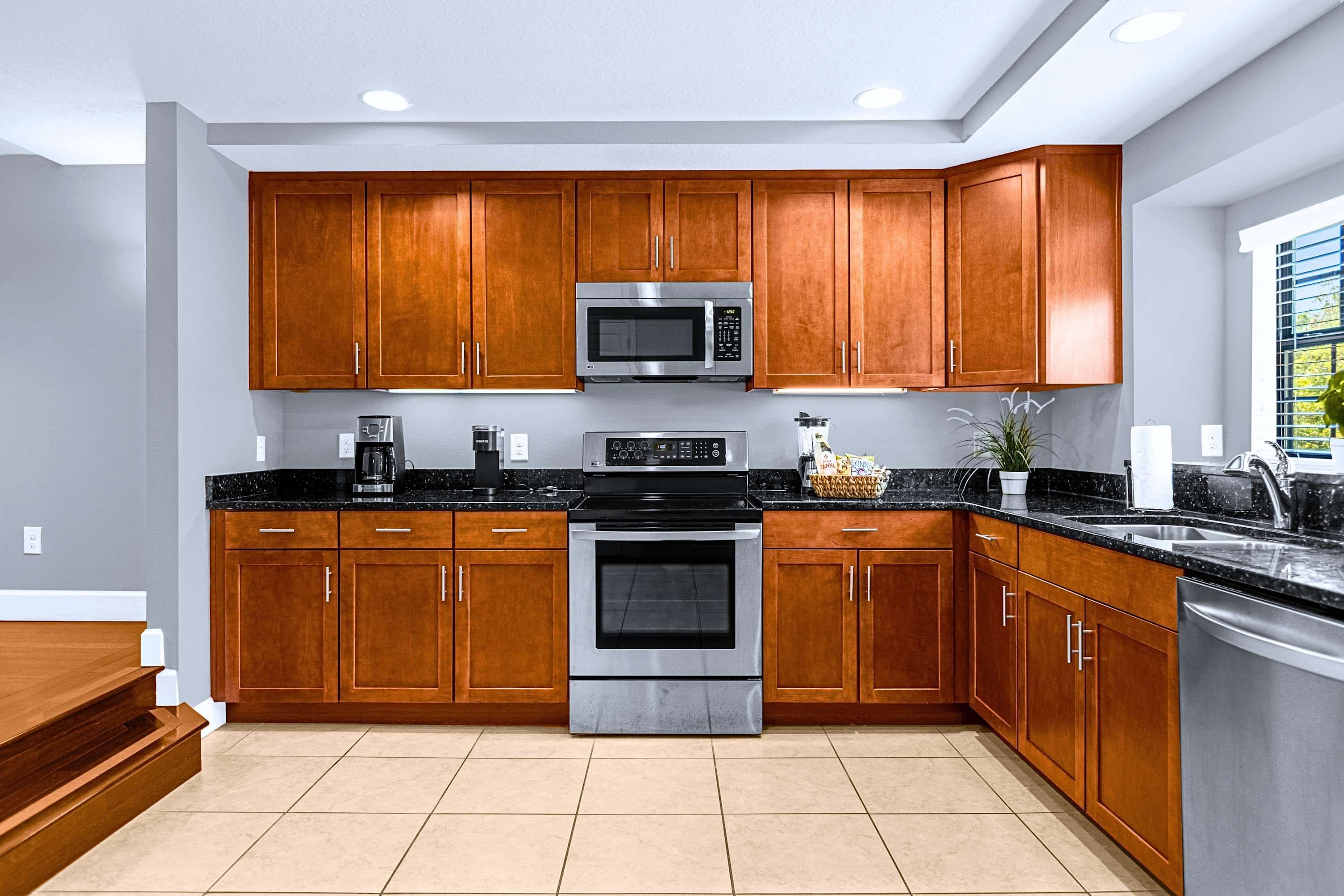 Una cocina moderna con armarios de madera, electrodomésticos de acero inoxidable y encimera negra.