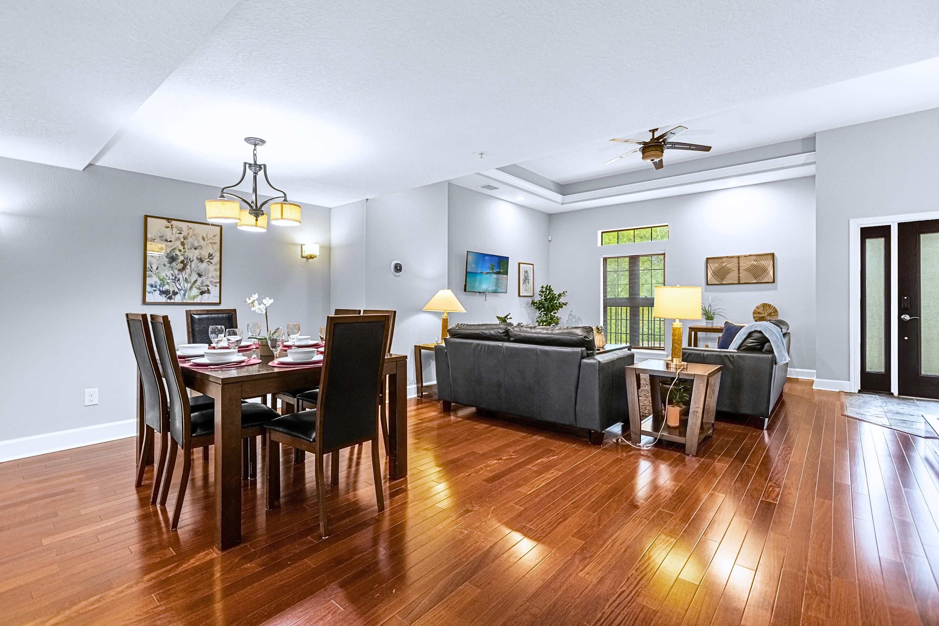 Ampla sala de estar com mesa de jantar, sofás e ventilador de teto.
