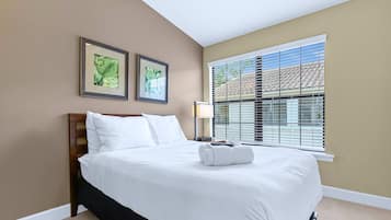 Una habitación de hotel con cama, mesita de noche, lámpara y dos cuadros en la pared.
