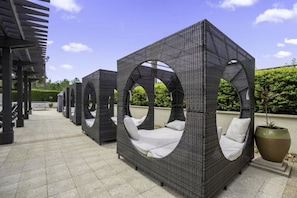Outdoor wicker seating with circular cutouts, a tiled patio, and a large planter. - Spacious Resort Home Near Disney - Pool, Hot Tub (Orlando)