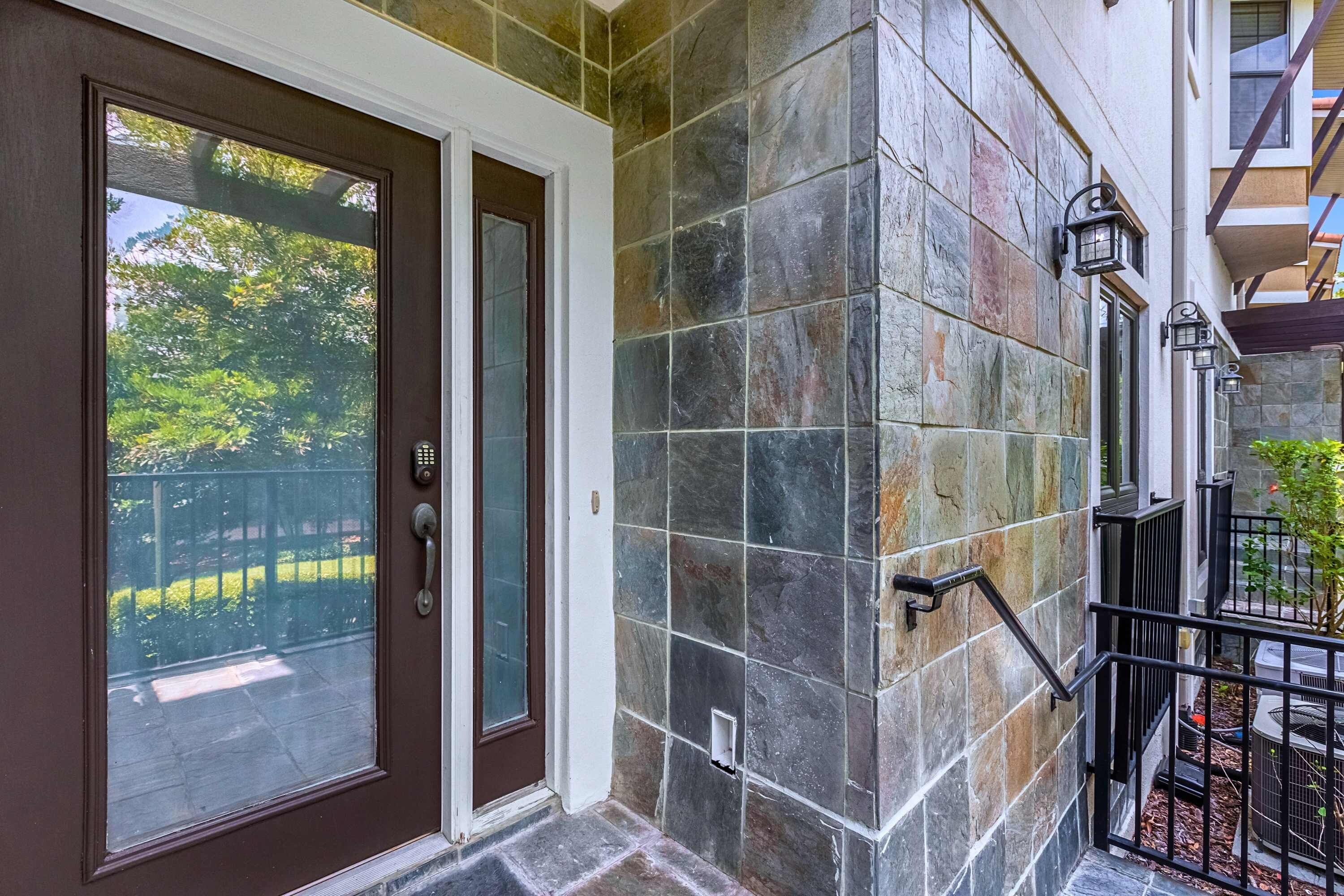 A building entrance with a brown door, stone wall, and a small window.