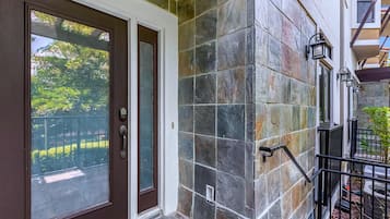 A building entrance with a brown door, stone wall, and a small window.