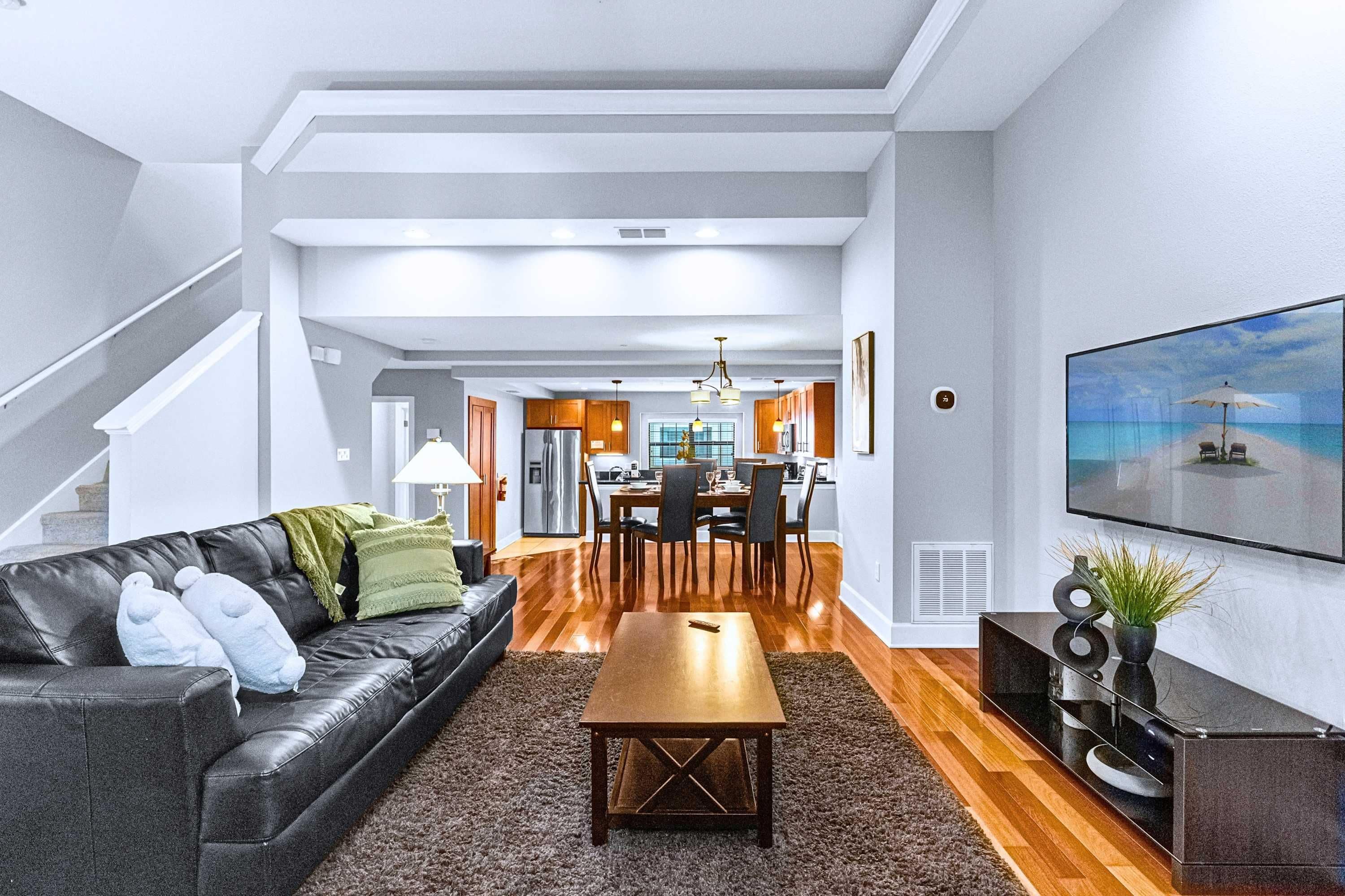 Una sala de estar moderna con un sofá de cuero, una mesa de centro de madera y un comedor con una cocina al fondo.