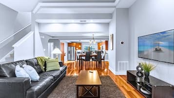 Una sala de estar moderna con un sofá de cuero, una mesa de centro de madera y un comedor con una cocina al fondo.