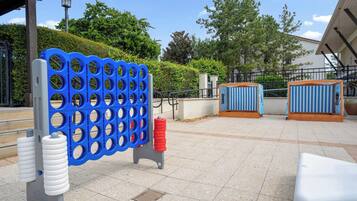 An outdoor seating area with a blue and white striped table, a metal fence, and a paved walkway.