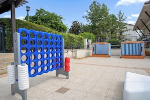 An outdoor seating area with a blue and white striped table, a metal fence, and a paved walkway. - Spacious Resort Home Near Disney - Pool, Hot Tub (Orlando)