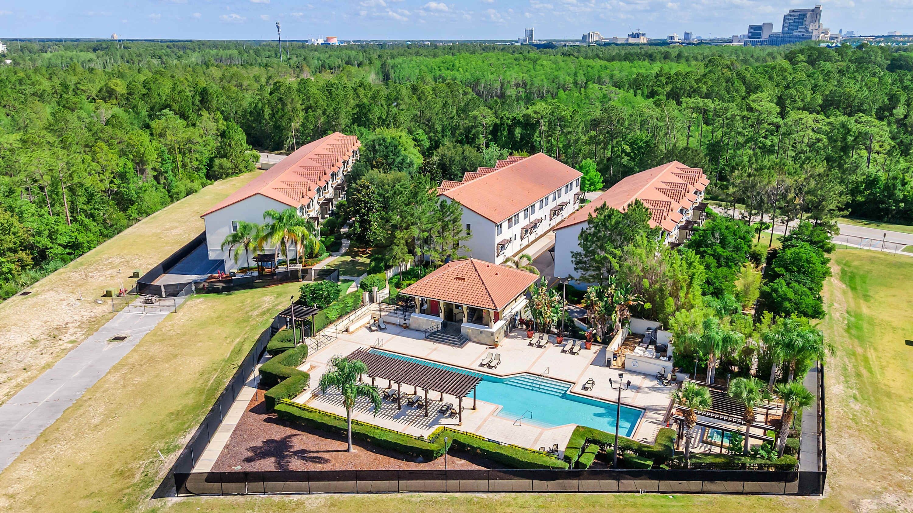 Resort com vários edifícios, piscina e floresta ao redor.