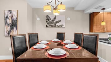 A dining area with a wooden table set for six, surrounded by black leather chairs.