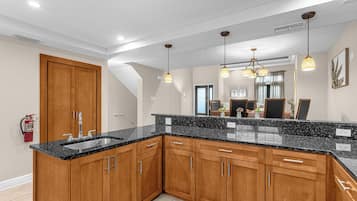 Una cocina moderna con armarios de madera, encimera de granito e iluminación colgante.