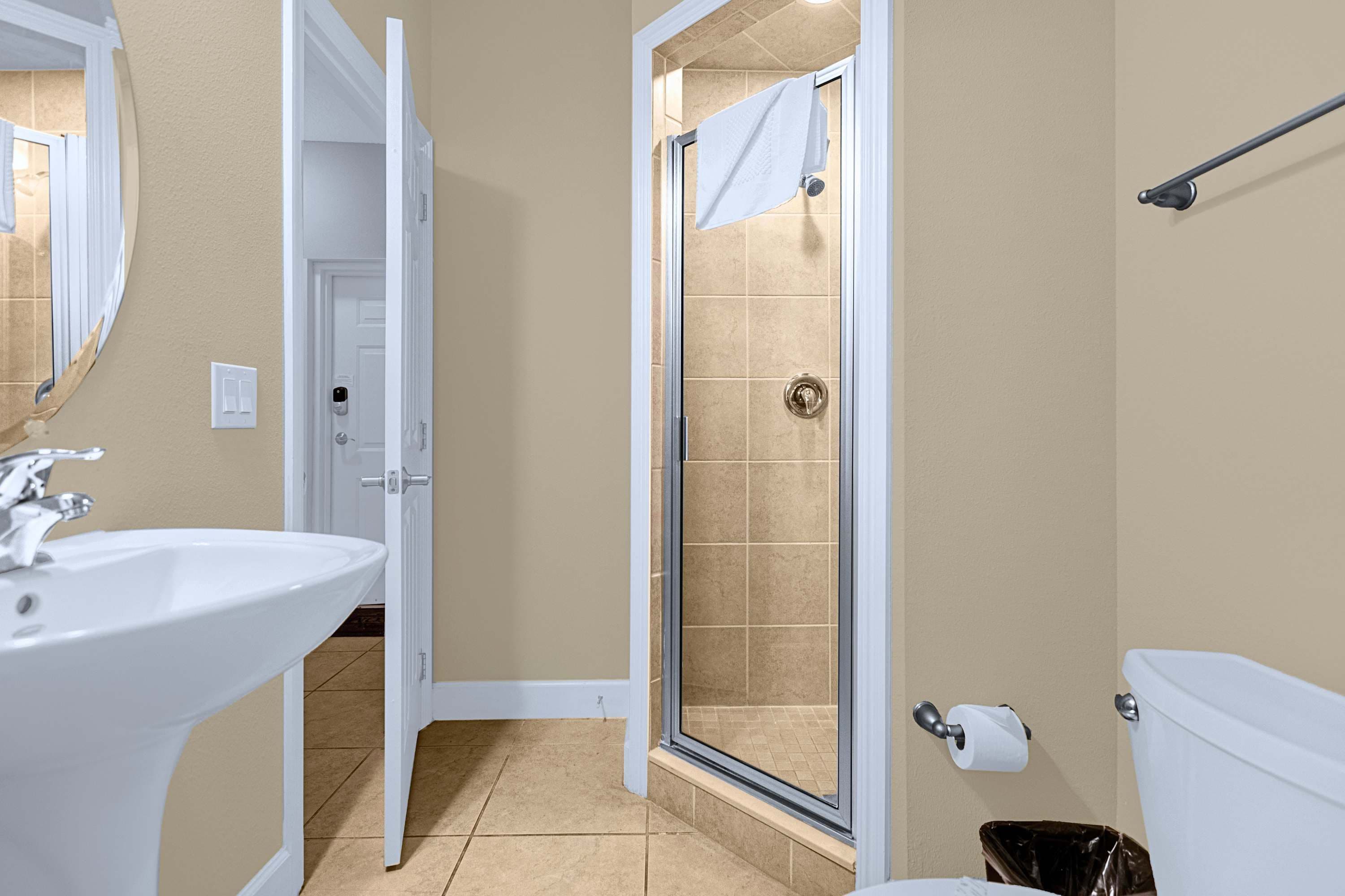 A bathroom with a white sink, a shower with a glass door, and a toilet.