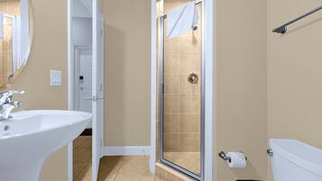 A bathroom with a white sink, a shower with a glass door, and a toilet.