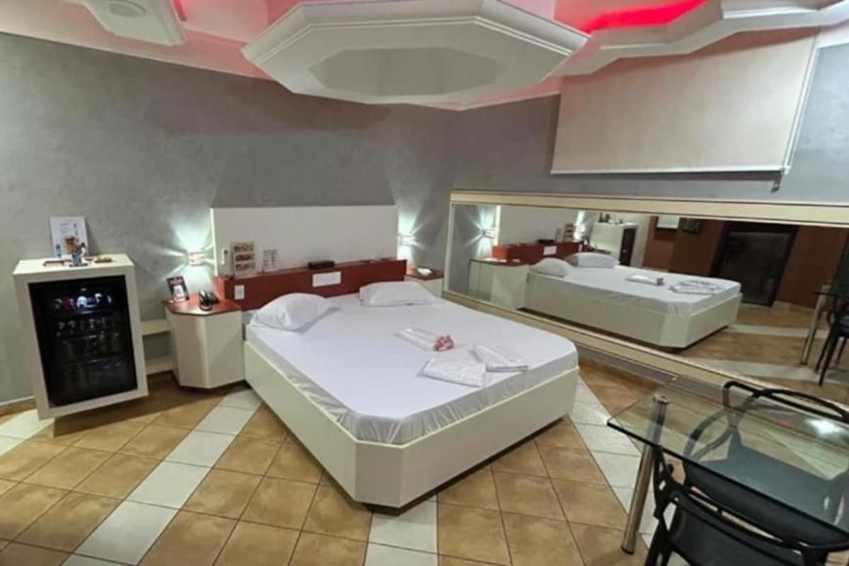 Une chambre d’hôtel équipée d’un lit, d’un bureau, d’une chaise, d’un miroir et d’un mini-bar.