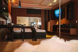 A modern hotel room with a bed, a desk, a chair, a television, and a large mirror. - Romanus Piracicaba (Piracicaba)