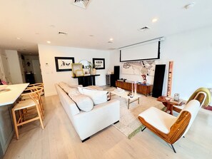 Een moderne woonkamer met een bank, stoelen, een salontafel en een eethoek met een tafel en stoelen.