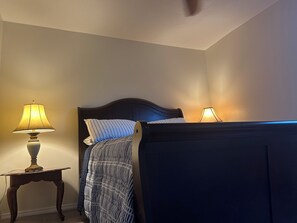 Un dormitorio con una cama, dos lámparas de noche y una mesita.