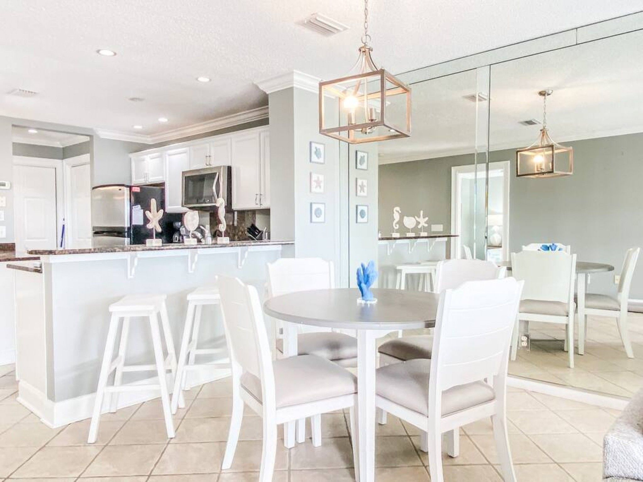 A modern kitchen with white cabinetry, a central island, and a dining area with white chairs and a round table.