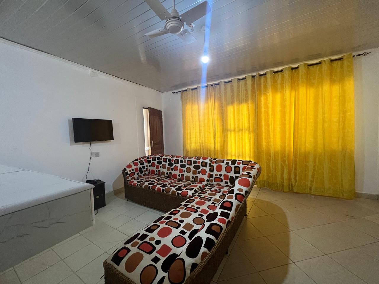 Una habitación con sofá, televisión y ventilador de techo.