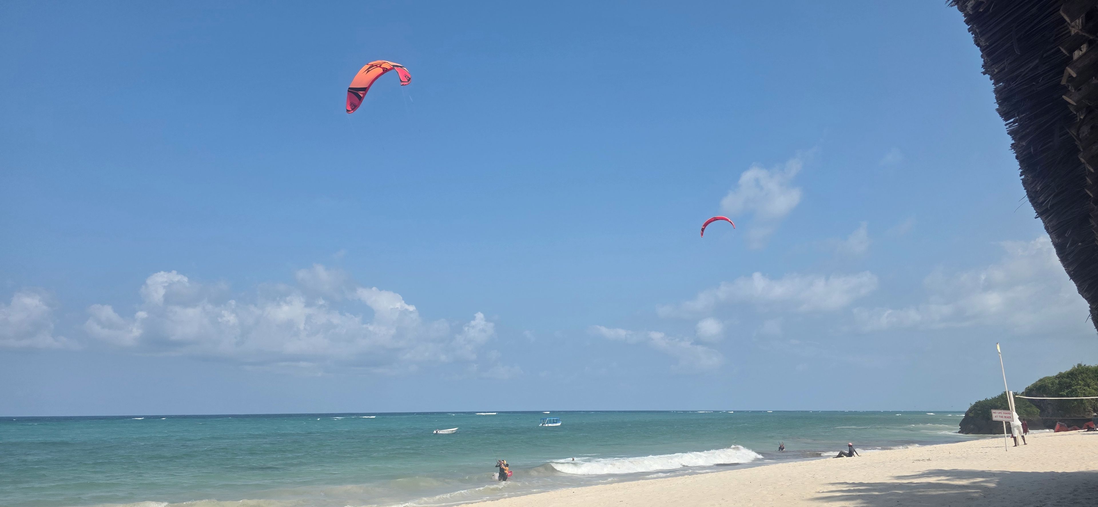 A beach with clear skies, a few people, and a boat in the water.
