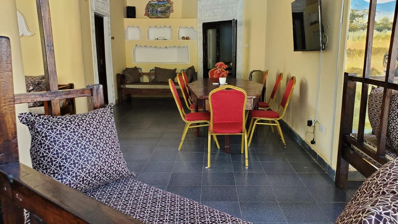 A dining area with a table and chairs, a sofa, and a patterned wall.