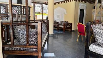 A spacious indoor area with wooden furniture, including a bench and chairs, and a tiled floor.
