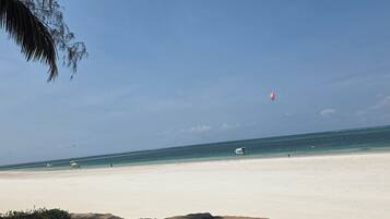Ein Strand mit blauem Himmel, sandigem Ufer und einigen Booten im Wasser.