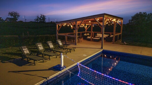 A swimming pool with lounge chairs and a covered seating area.