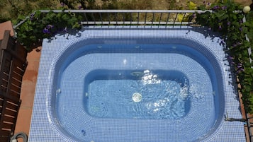 Una bañera de hidromasaje rectangular con interior de azulejos y barandilla metálica alrededor.