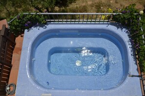 Banyera hidromassatge rectangular amb interior de rajola i barana metàl·lica al voltant.