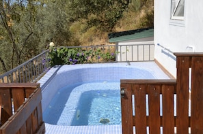 A swimming pool with a tiled edge, surrounded by a wooden deck and a metal railing.