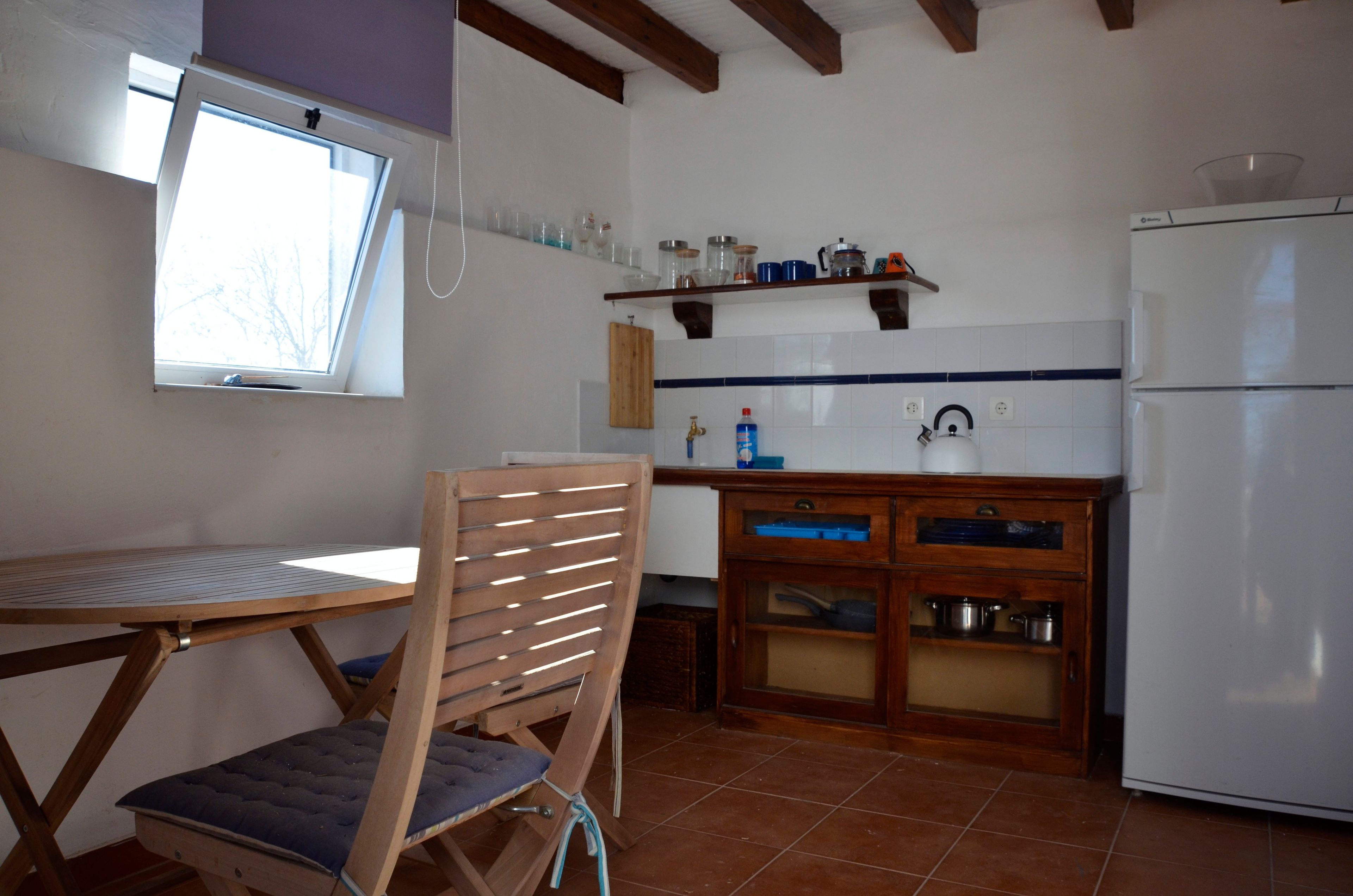 Una cocina compacta con mesa, una silla, un mueble empotrado y un refrigerador blanco.