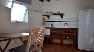 Una cocina compacta con mesa, una silla, un mueble empotrado y un refrigerador blanco.