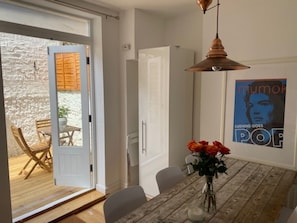 A dining area with a wooden table, chairs, a vase with flowers, and a poster on the wall. - Contemporary 4BDR Townhouse by North Laine (Brighton and Hove)
