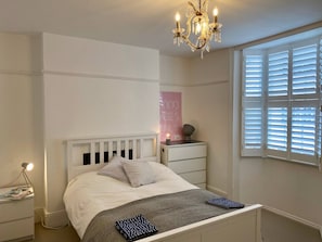A bedroom with a bed, bedside tables, a nightstand, a lamp, a chandelier, a window with blinds, and a poster on the wall. - Contemporary 4BDR Townhouse by North Laine (Brighton and Hove)